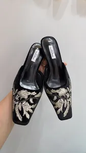 Vista detallada de mules de terciopelo negro con elegante bordado floral para mujer
