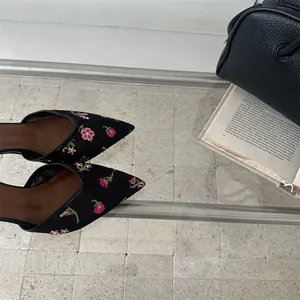 Detalle de manoletinas vintage de malla negra con delicados bordados de flores rosas