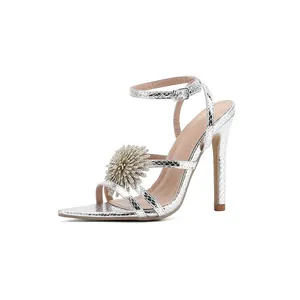 Elegantes sandalias plateadas de tacón de aguja con flor de cristal y cierre de correa.