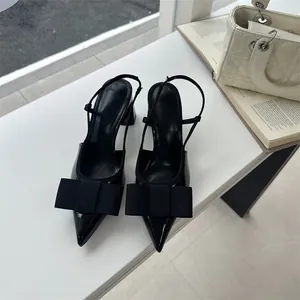 Close-up of black pointed-toe slingback heels featuring a large elegant bow