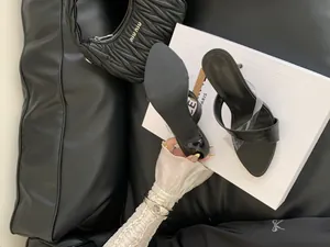 Détail de sandales à talons aiguilles noires à motif crocodile et bride en PVC.