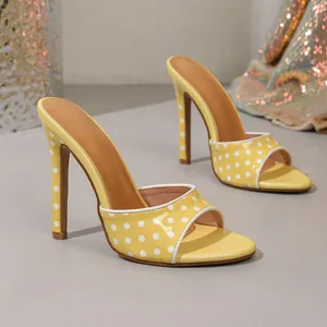 Detailed side view of yellow polka dot high-heeled mules with slim stiletto heels