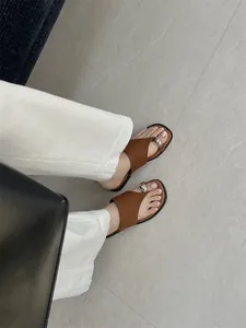 Elegante bruine teenring sandalen met metalen gesp op voeten voor de zomervakantie
