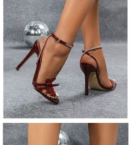 Nahaufnahme von weinroten Stöckelsandalen mit glitzernden Schmetterlings-Strassdetails für Partys.