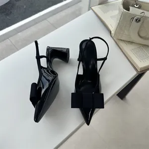 Close-up of black patent slingback heels with elegant bow detail on pointed toe
