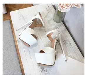 Top-down view of white platform stiletto sandals on a rustic white wooden background