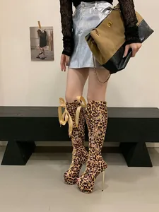 Striking leopard print knee-high cutout boots featuring platform heels and a yellow bow