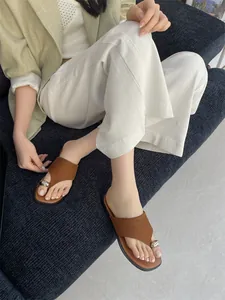 Detailweergave van stijlvolle bruine teenslippers met zilveren kraal op voeten