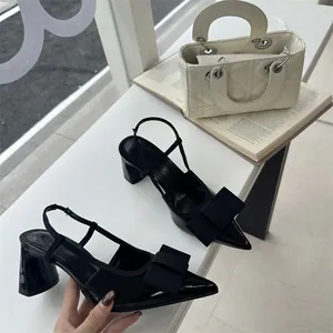 Elegant black slingback block heel pumps featuring a prominent bow and pointed toe detail