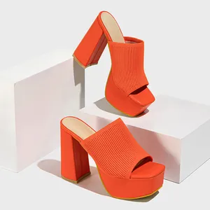 Close-up of orange knit platform sandals with chunky heels and square toe design.