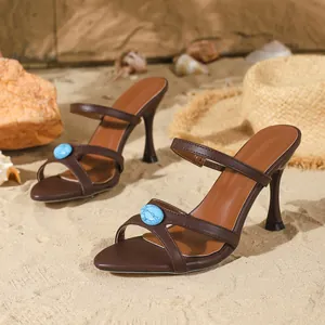 Vue détaillée de sandales à talons aiguilles marron avec pierre turquoise sur sable
