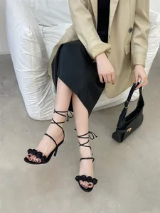 Elegante schwarze Riemchensandalen mit hohen Absätzen, Rosendekor und Stilettoabsatz.