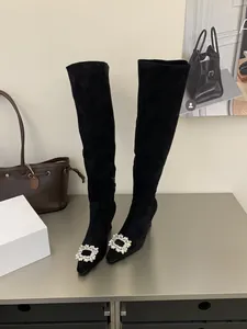 Elegant black suede pointed-toe over-the-knee boots featuring a sparkling crystal buckle
