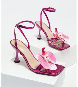 Detailed view of square toe pink stiletto sandals featuring a large 3D orchid flower decoration
