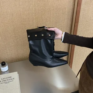 Detail view of black pointed-toe cuffed boots with silver studs and wedge heel.