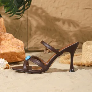 Détail de la sandale marron à talons hauts ornée d'une pierre précieuse bleue.