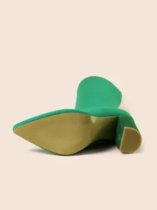 Detailopname van groene gebreide stretchlaars met focus op de zool en de blokhak