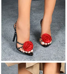 Detailed view of black stiletto sandals featuring large red 3D flowers and polka dots.