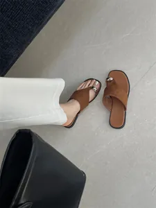 Retro bruine platte sandalen met stijlvolle gouden teenring op een strakke vloer