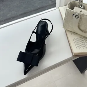 Close-up of black pointed-toe slingback heel with a large bow and block heel