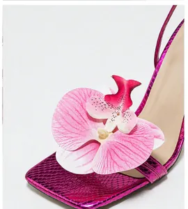 Close-up of 3D orchid flower on pink metallic snakeskin square toe high heel sandals