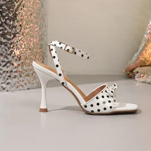 Elegante zijaanzicht van een witte polka dot sandaal met strik en een enkelbandje