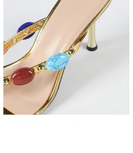 Close-up detail of colorful oval gemstones and studs on golden bohemian high heel sandals