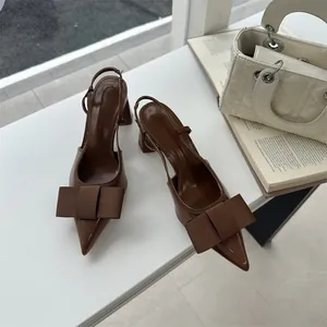 Close-up of brown pointed-toe slingback heels with a large bow and block heel.