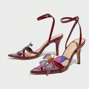 Close-up of burgundy patent leather sandals with vibrant 3D butterfly embellishments