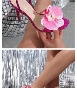 Detailopname van een grote roze orchidee decoratie op een fuchsia sandaal met hoge hakken