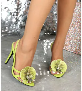 Detail of lime green high heel sandals featuring an elegant 3D orchid flower decoration.
