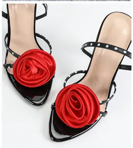 Detailed macro view of elegant black high heels featuring a large red fabric rose decoration