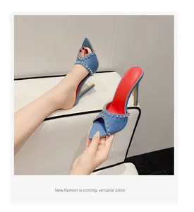 Detail van stijlvolle denim sandalen met hoge hak, zilveren studs en rode zool