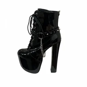 Detailed side view of black patent leather platform boots with metal chains and studs