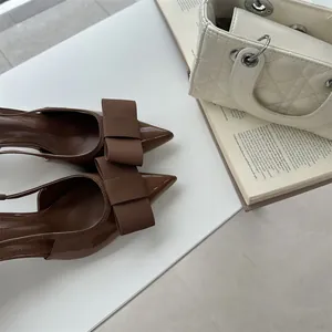 Elegant brown pointed-toe slingback high heels featuring a classic ribbed ribbon bow detail.