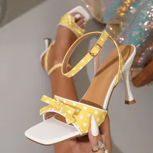 Detailopname van een gele sandalen met hoge hakken, stippenpatroon, strik en enkelbandje
