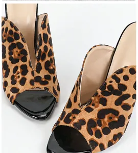 Primer plano del estampado de leopardo y charol negro en sandalias de tacón de aguja