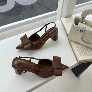 Elegant brown slingback pumps with bow detail and chunky heel on a display ledge
