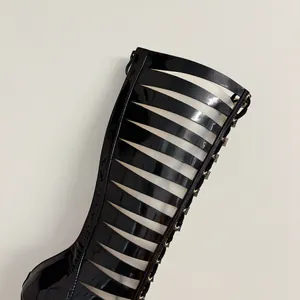 Detailed close-up of sexy black patent leather hollow-out stiletto gladiator boots.