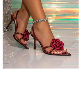 Detailed view of wine red patent leather high heel sandals with a 3D fabric rose.