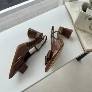 Macro view of brown patent leather slingback heels featuring bow detail and sturdy block heel