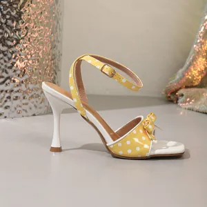 Zijaanzicht van gele polkadot sandalen met strik, vierkante neus en naaldhakken