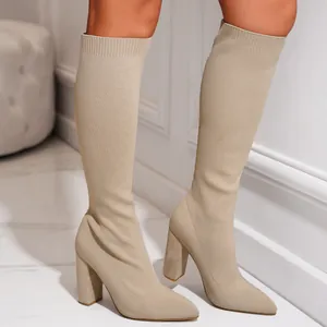 Detailopname van beige gebreide stretchlaarzen met puntige neus en stevige hak