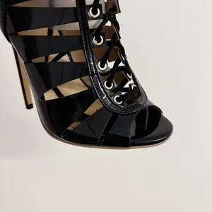 Detail of black patent leather lace-up high heels with gold eyelets and stiletto
