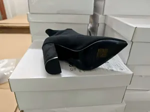 Black knitted pointed-toe boot with chunky heel displayed on white shoeboxes