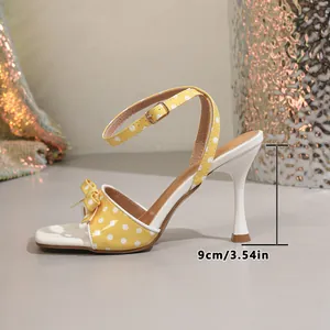 Gedetailleerd zijaanzicht van gele stiletto sandaal met stippen en 9 cm hakhoogte.