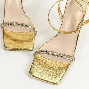 Macro view of gold square-toe high-heel sandals with rhinestone strap details