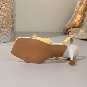 Detailopname van gele polkadot sandaal met hoge hak, vierkante neus en slanke hak