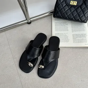 Close-up van vintage zwarte platte teenslippers met een metalen knoopversiering erop