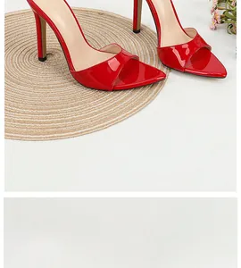Close-up of elegant red patent leather pointed toe stiletto sandals on woven mat